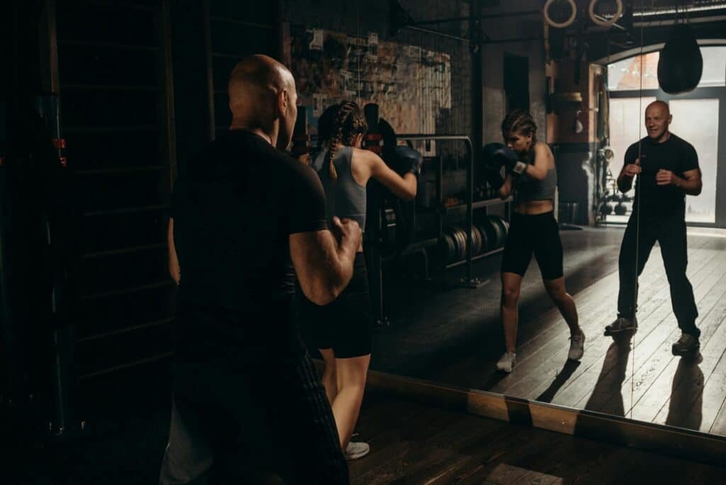 Woman and coach practising some beginner boxing moves in a mirror