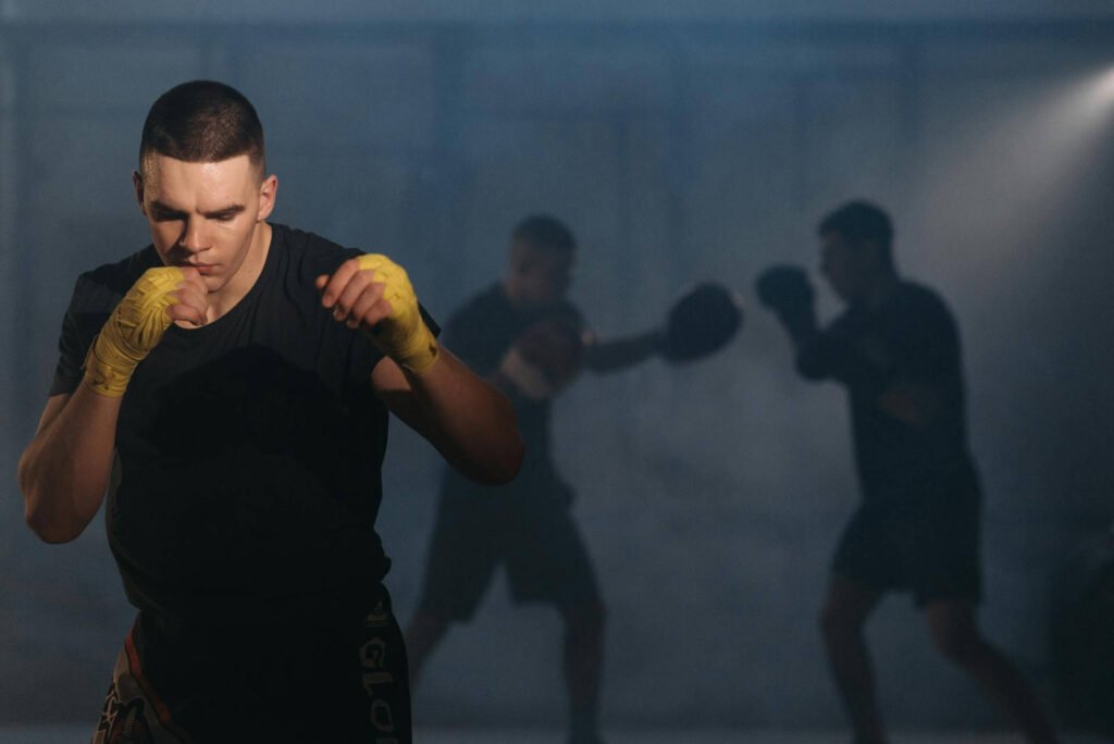 boxer shadowing boxing with his coach doing pad work in the background