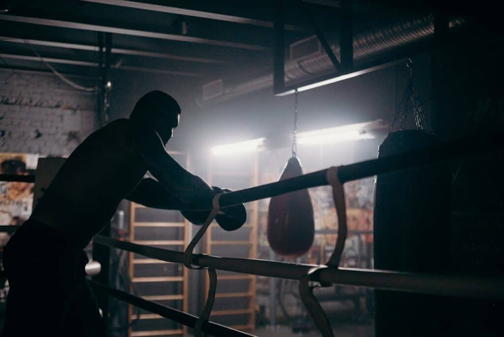 A boxer reflects after a shadowboxing session in a dark gym