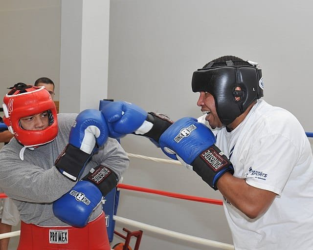 two boxers sparring in heavy gloves with headgear