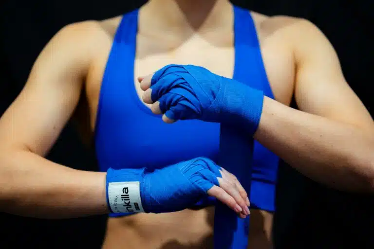 A female boxer wrapping her hands with blue boxing hand wraps