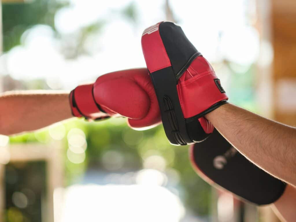 A red boxing glove hits a pad in boxing training