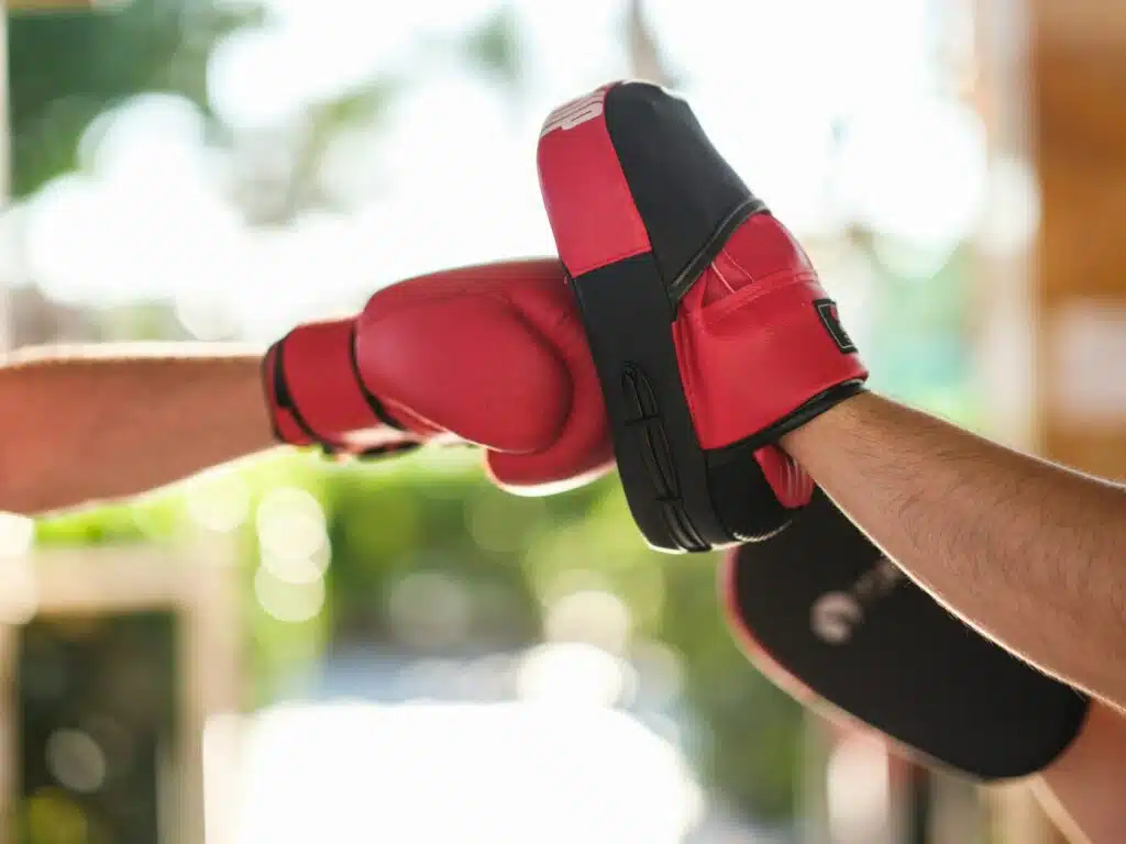 A red boxing glove hits a pad in boxing training