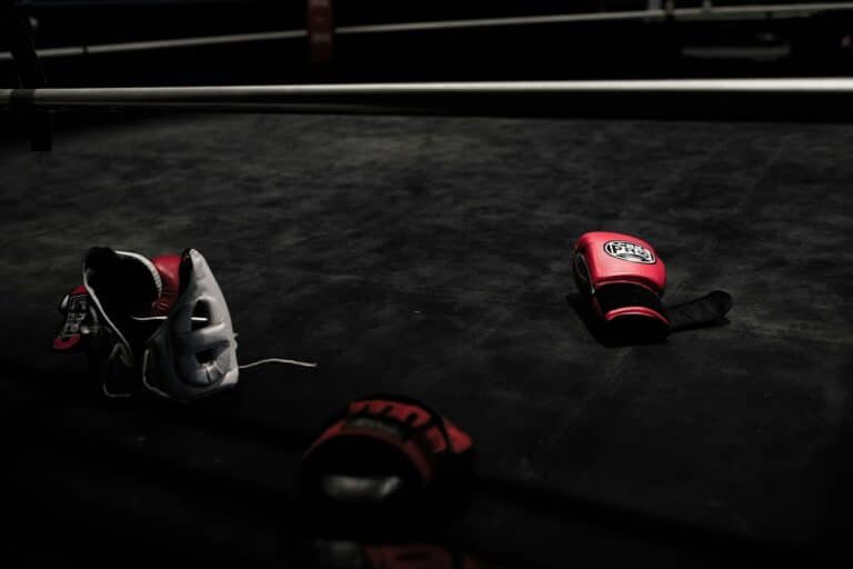 Boxing gloves and head gear lay on a boxing ring mat