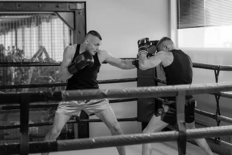Two boxers sparring in a boxing ring with heavy sparring gloves