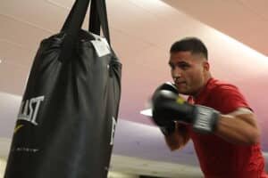 A boxer wearing in his boxing gloves on the heavy bag
