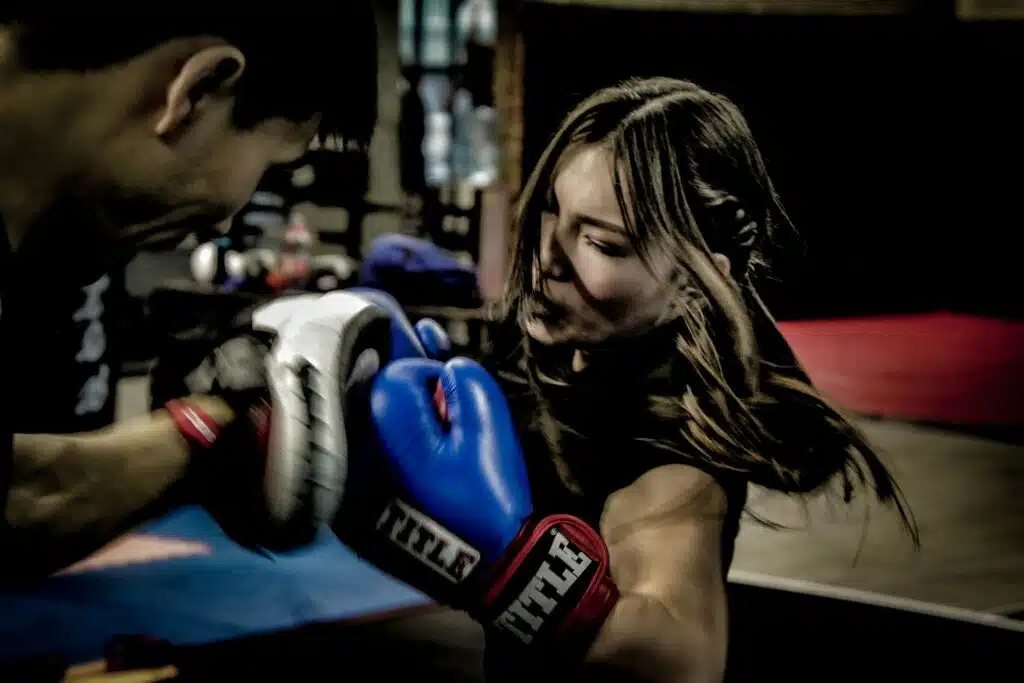 Female boxer works the uppercut on the pads with her coach