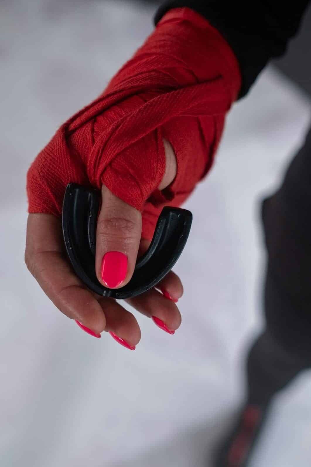 A hand holding an new mouthguard in boxing wraps