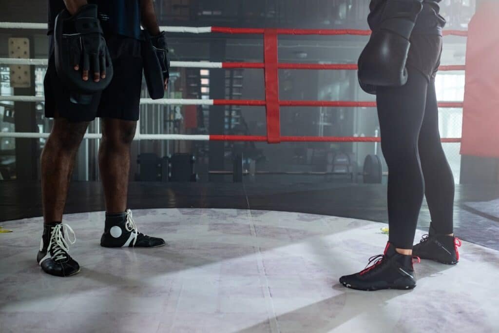 A boxer and coach both wear boxing shoes in a boxing ring